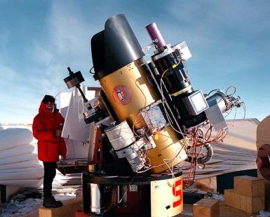 Man standing next to a large telescope in Antarctica