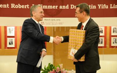 President Zimmer (left) shakes hands with Justin Yifu Lin, PhD'86 (right)