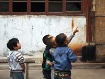 Chinese children standing close together and pointing at something off-screen