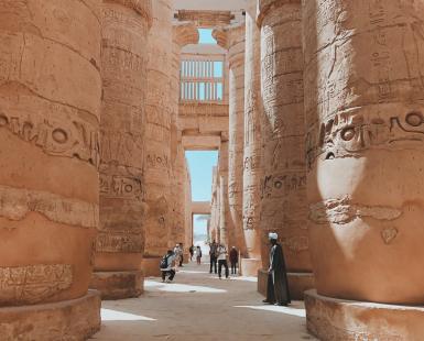 People walking through large brown pillars