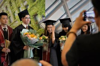 Students in academic regalia have their photos taken by family members