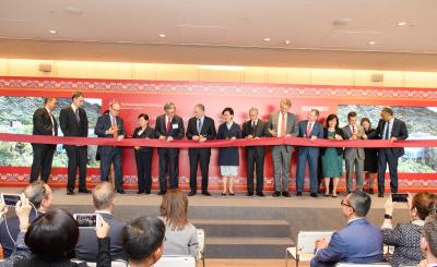 Many people in suits on stage cutting a ribbon