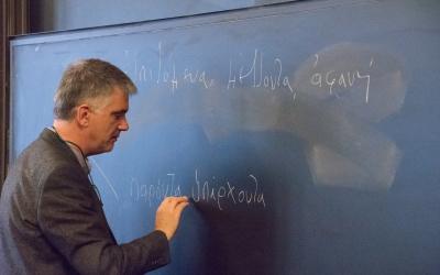 A presenter writes Greek characters on the board