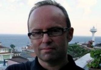 Man wearing black collared shirt and glasses posing for a picture