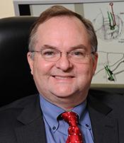 Photo of a man in a suit and tie smiling for a picture