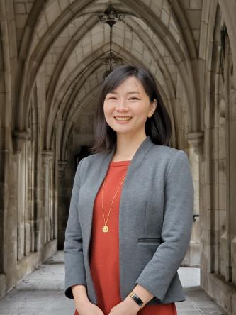 Woman wearing a gray suit and red shirt smiling for a picture